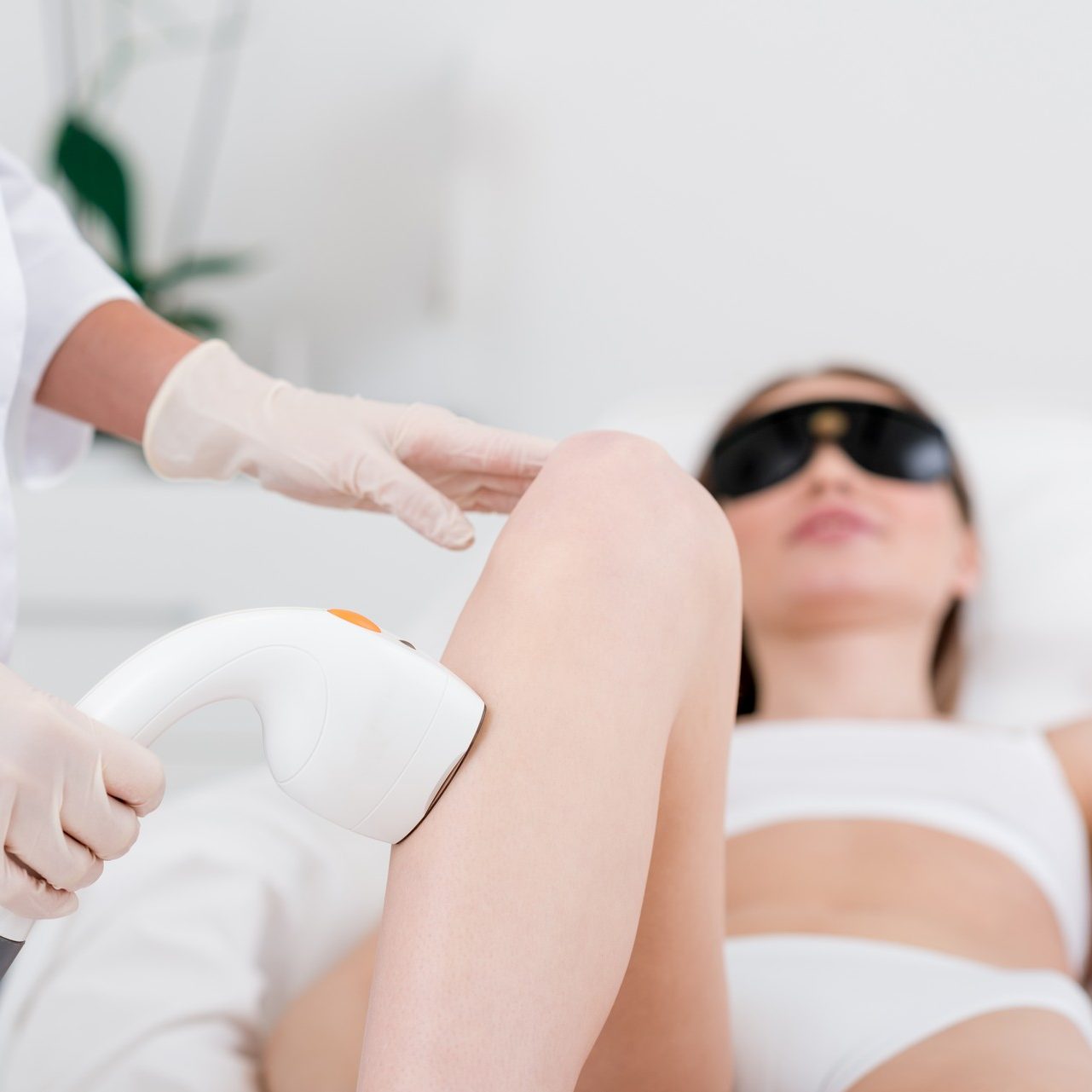 partial view of woman receiving laser hair removal epilation on leg in salon